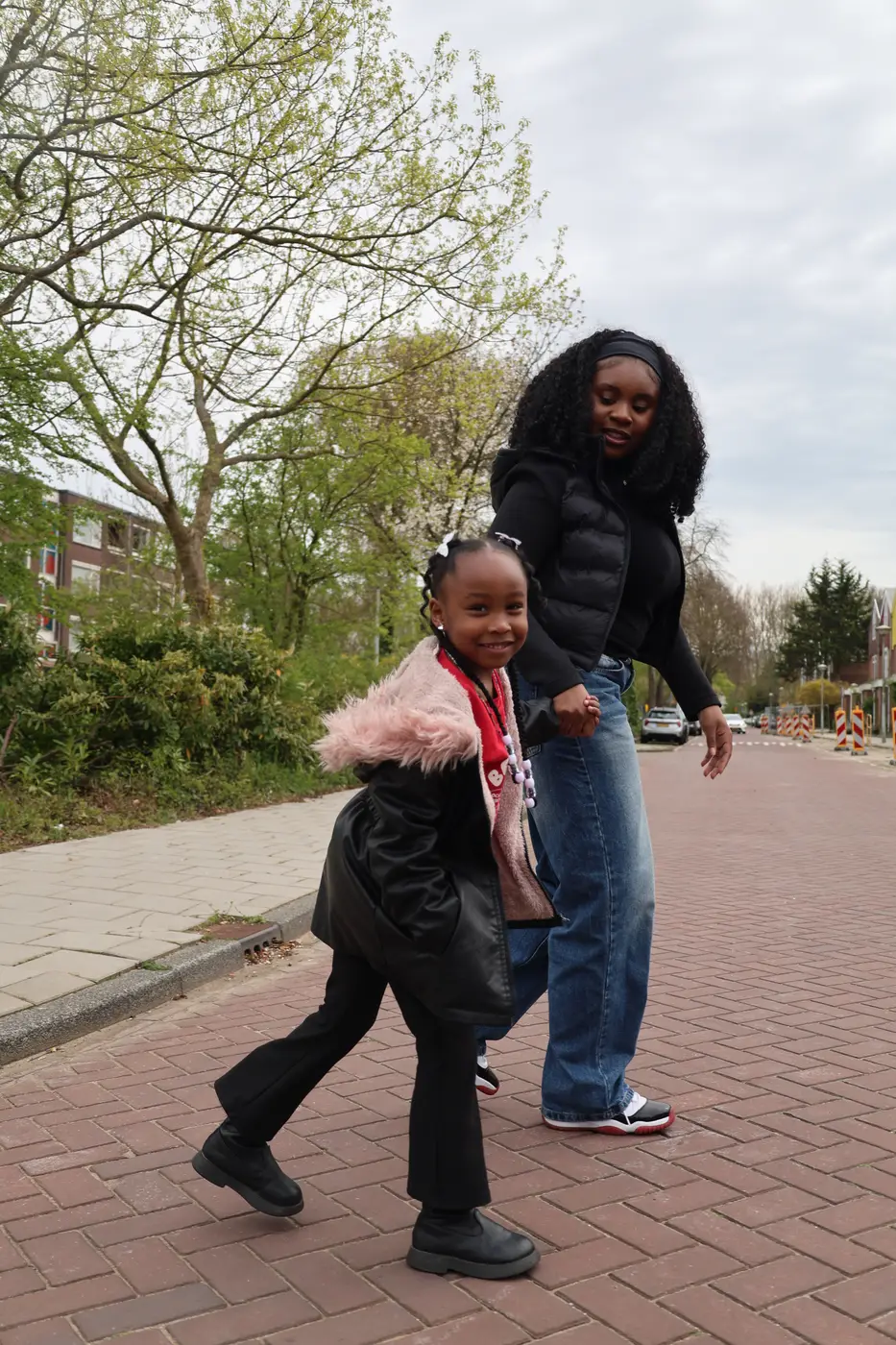 Buddy loopt hand in hand met een meisje over de stoep in de wijk