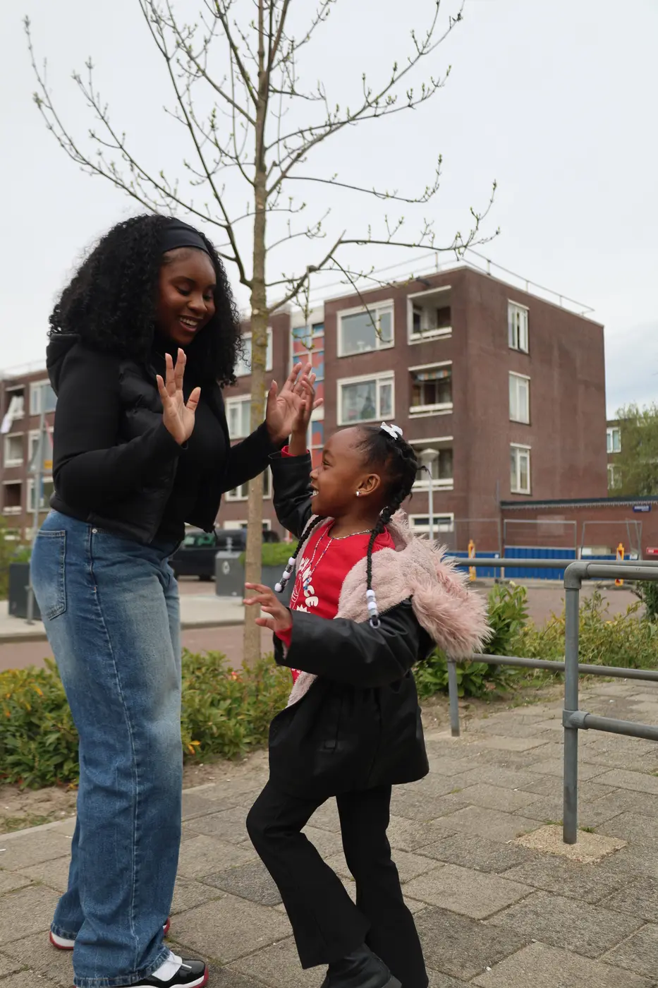 Buddy en meisje geven elkaar een high five op de stoep in de wijk